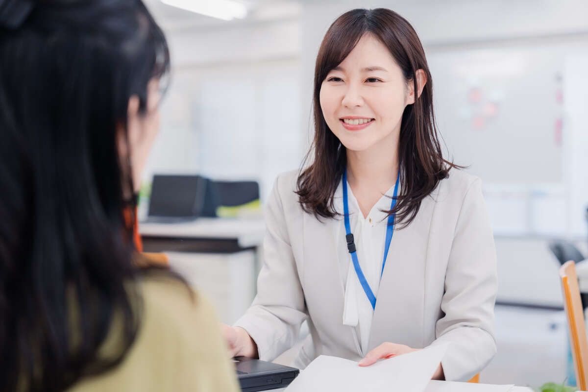 書類を見せながら笑顔で話す女性