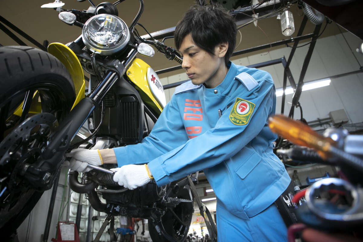 バイクのタイヤ周辺を整備する人