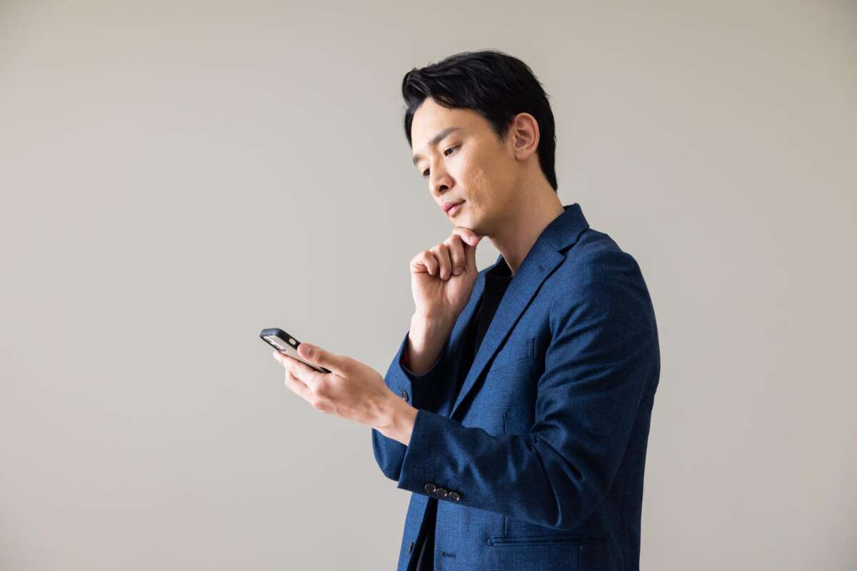 スマホを見て考え込む様子の男性