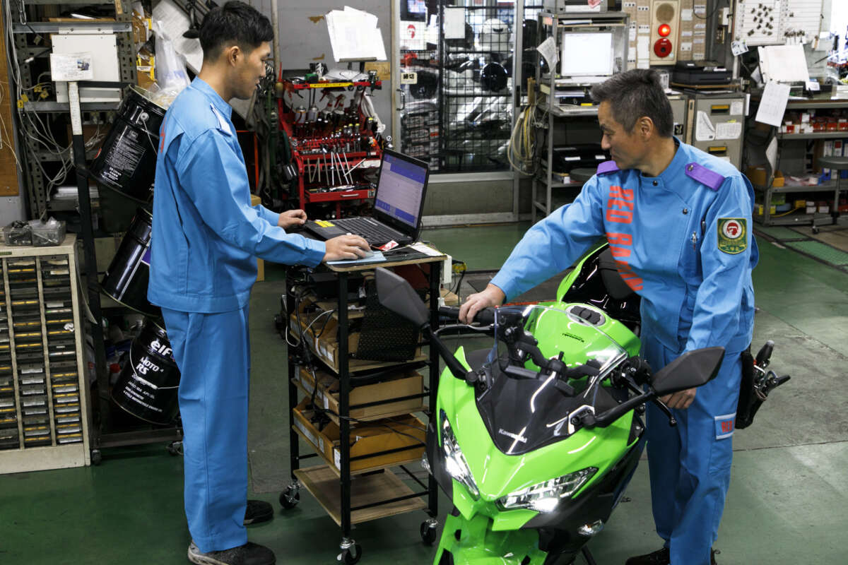 整備工場でバイクを点検しながら診断機を操作するレッドバロンの整備士