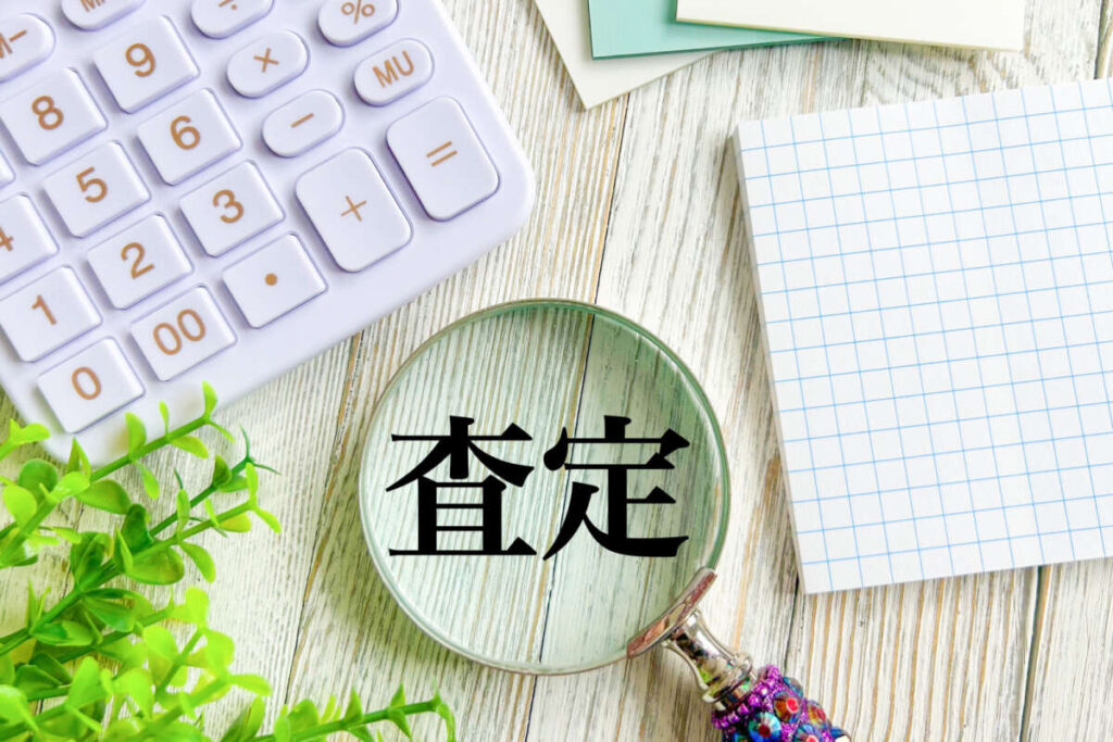 査定と書かれた文字と電卓、ノート