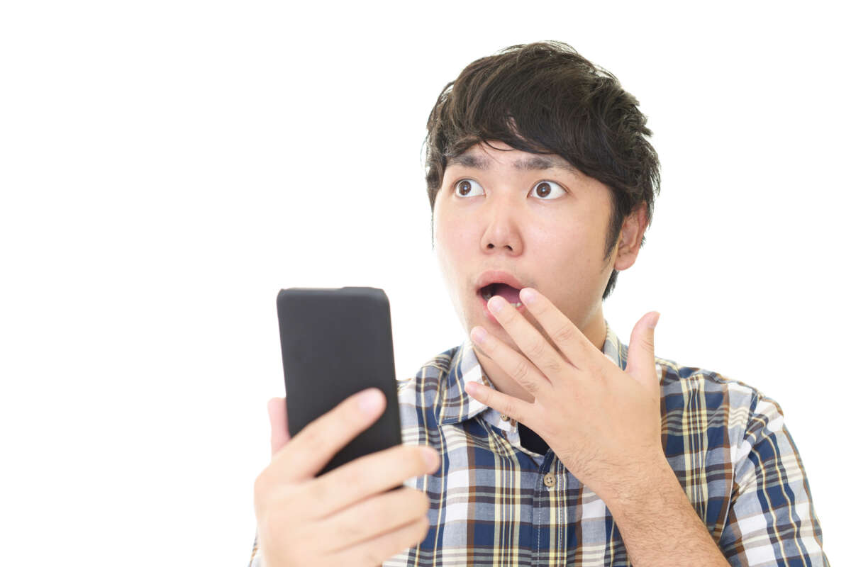 スマホを片手に驚いた表情をする男性