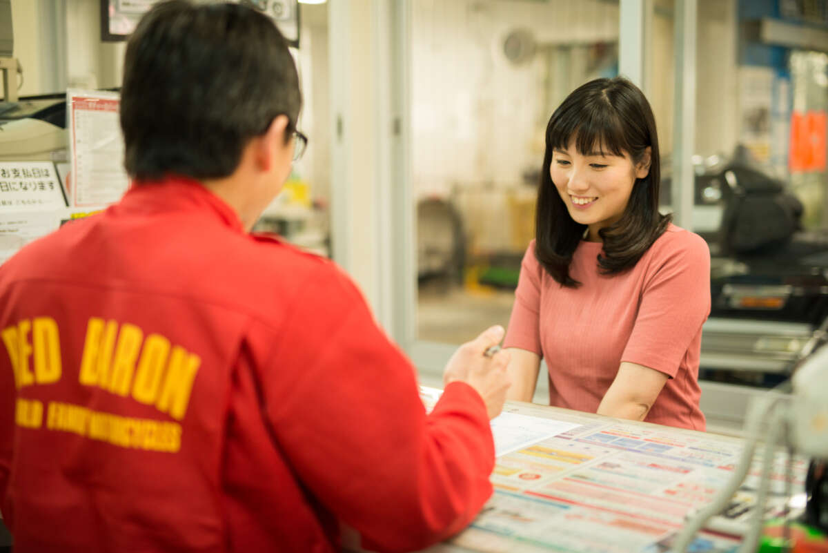 レッドバロンのカウンターでスタッフの説明を聞く女性