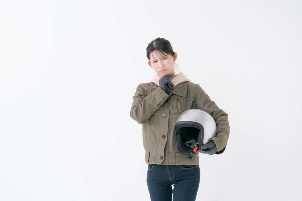 ヘルメットを持ち考える女性ライダー