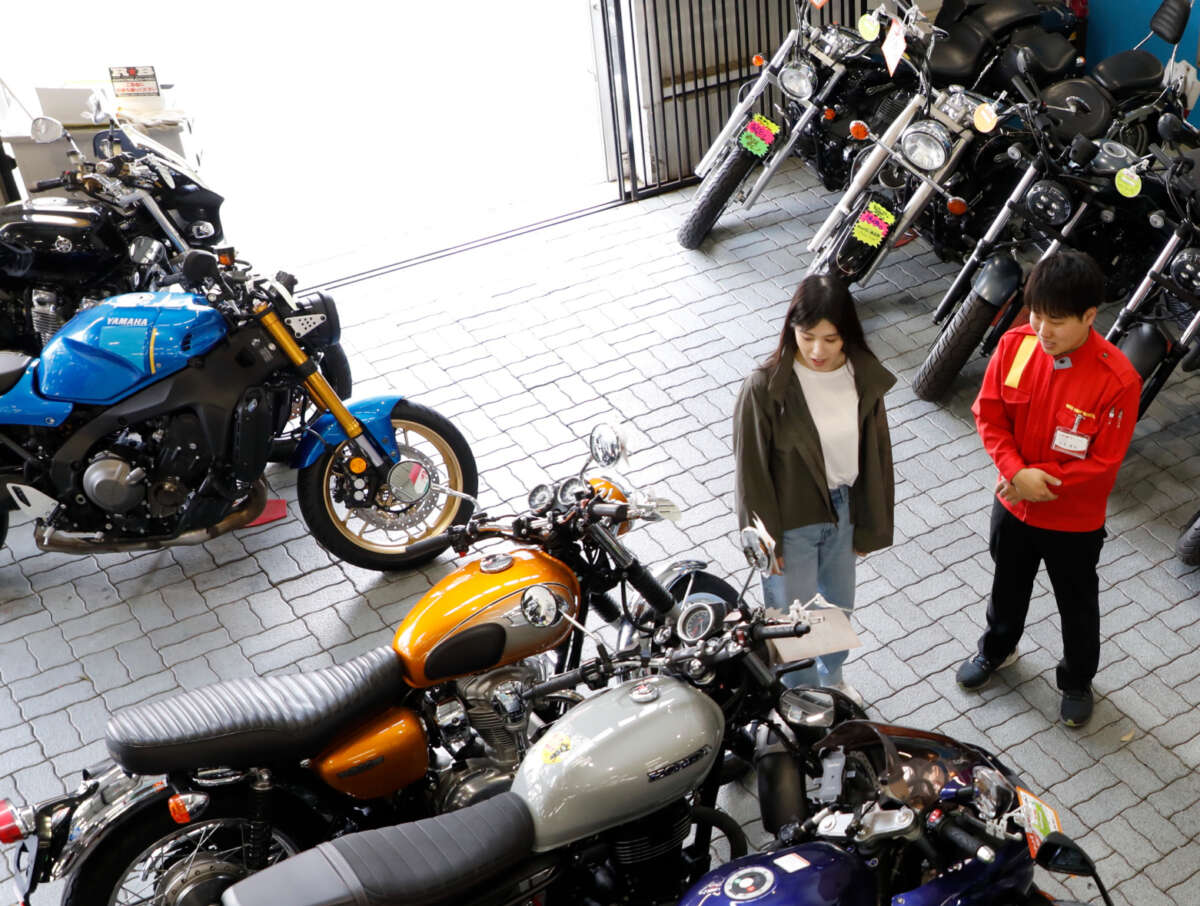 レッドバロン店内でスタッフと一緒にネオクラシックバイクを見ている女性客