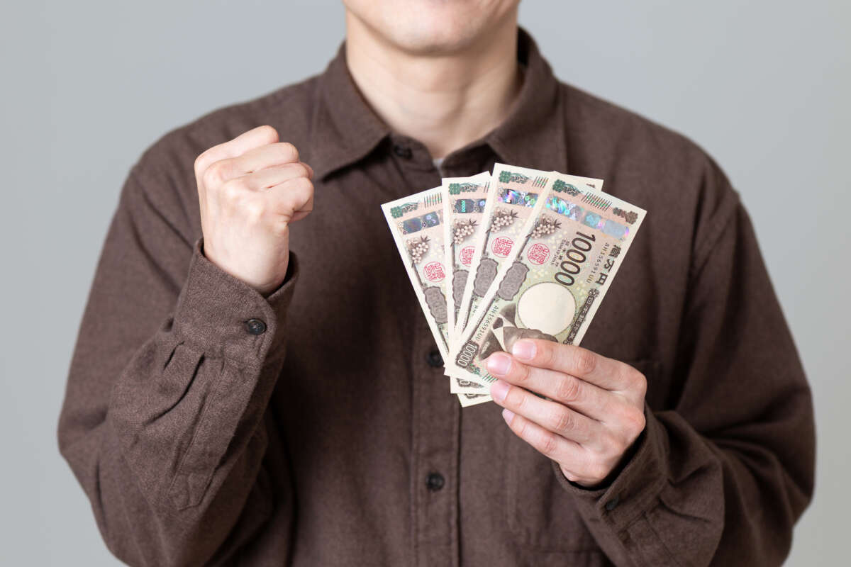 現金を持ちガッツポーズする男性