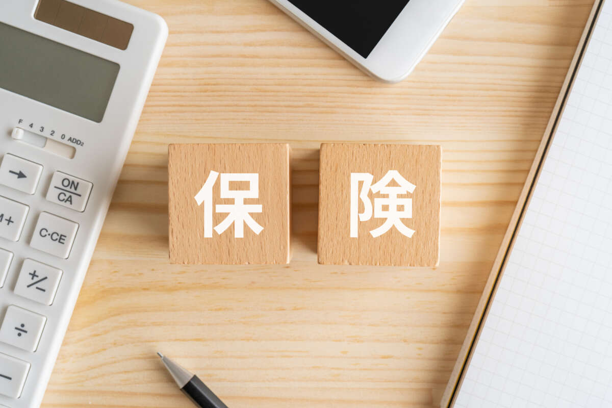 保険と書かれたブロック、電卓、スマホ、ノート