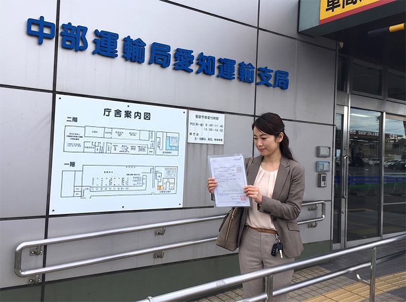 中部運輸局愛知運輸支局の庁舎前で書類を持つ女性