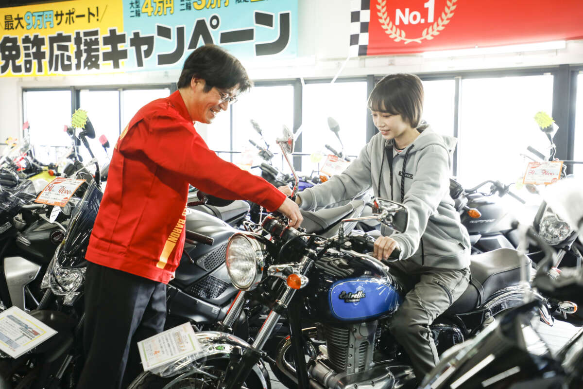 バイクショップでスタッフから車両の操作説明を受ける女性