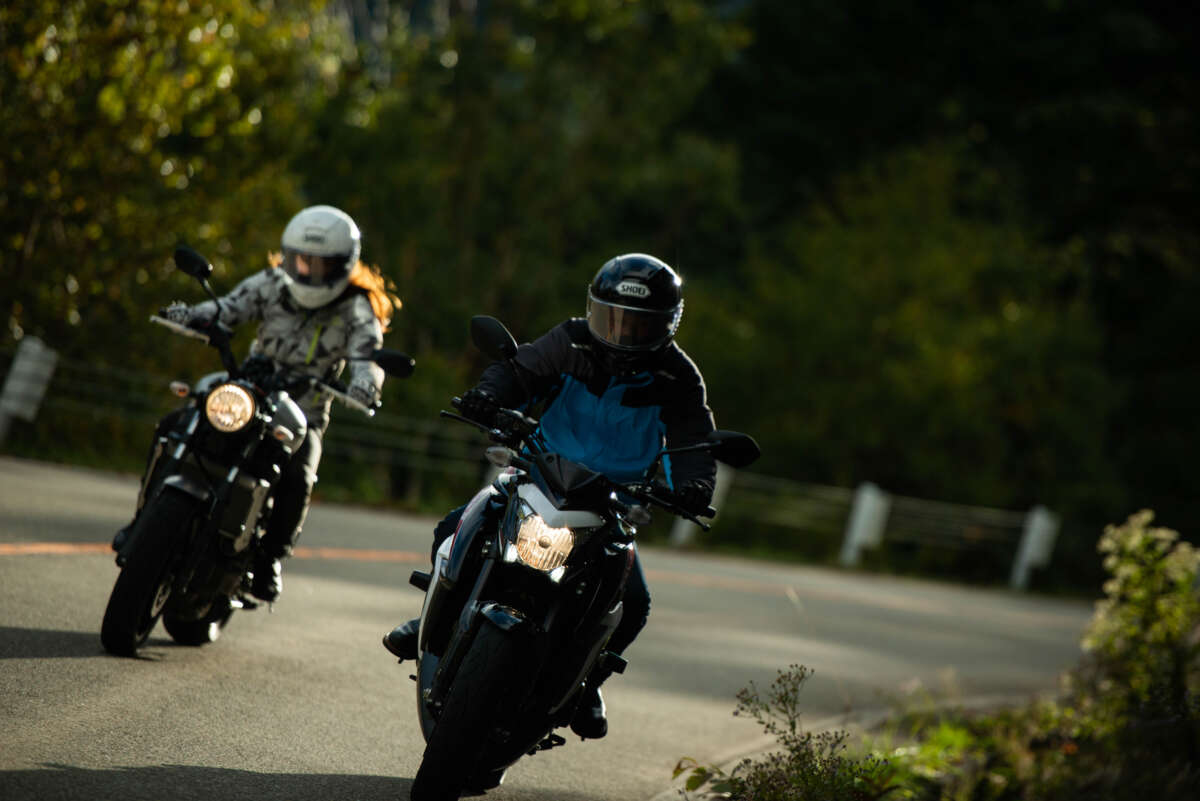 ワインディングロードを走行する2台のネイキッドバイクとライダー