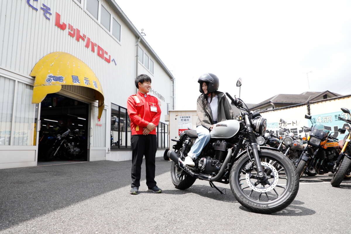 レッドバロンの店先で微笑むスタッフとバイクにまたがる女性ライダー