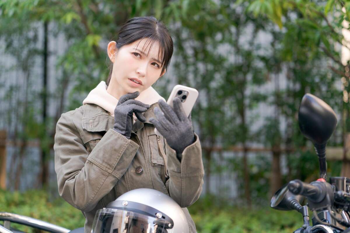 スマホを片手に悩む女性ライダー